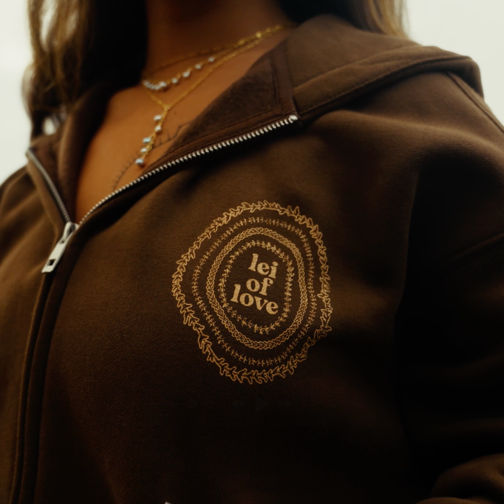 Brown jacket with 'lei of love' print on a blurred background