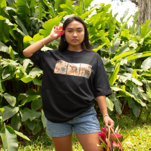 Woman standing in a lush green garden wearing a black t-shirt with a graphic design.